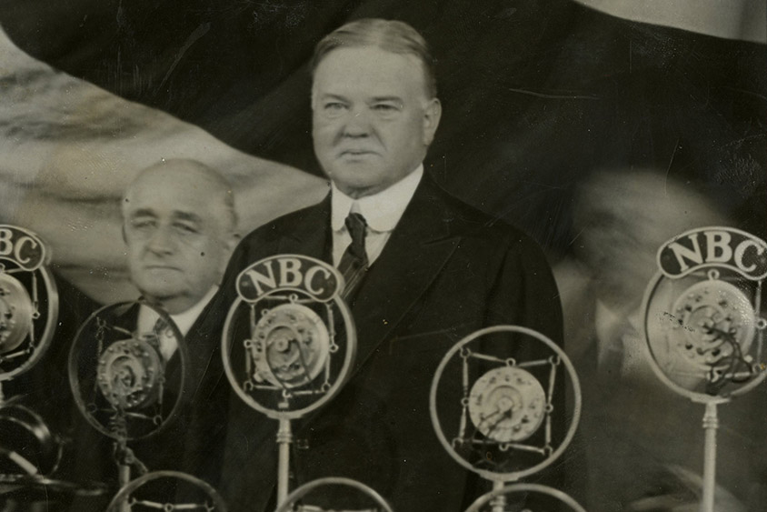 President Hoover standing before the microphones at the annual meeting of The Associated Press at the Waldorf Astoria Hotel, 04/22/1929. Here he delivered his first public address since the inauguration.