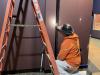 Worker paints wall trim in Museum gallery, March 18, 2026