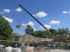 Workers in a basket being lifted by a crane to demolish the chimney, May 14, 2025