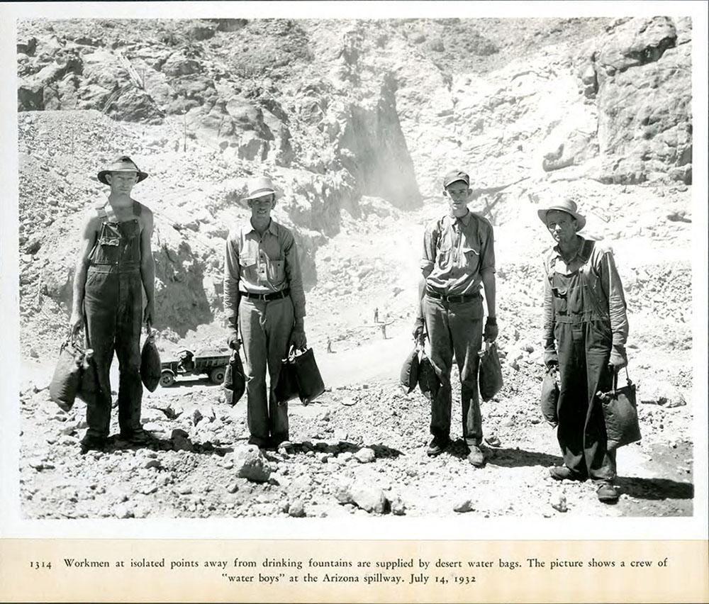 Workers at dam site carrying desert water bags.07/14/1932