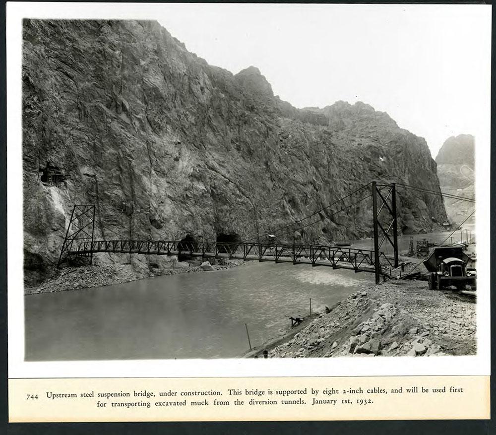 Upstream steel suspension bridge under construction, will first be used for transporting excavated muck from the diversion tunnels. 01/01/1932