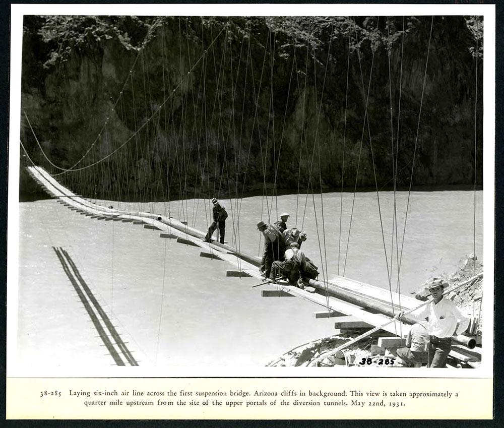 Workers laying a 6 inch air line across the first suspension bridge. 05/22/1931