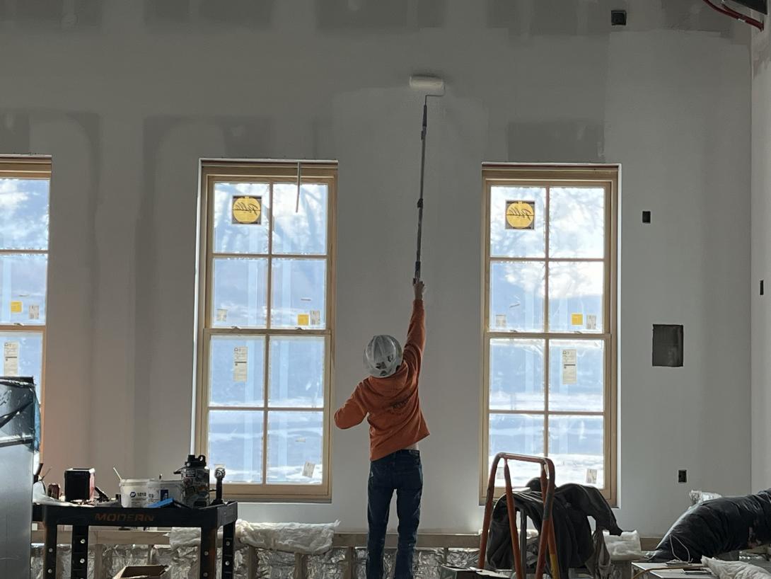 Worker paints wall of new lobby addition, December 23, 2025