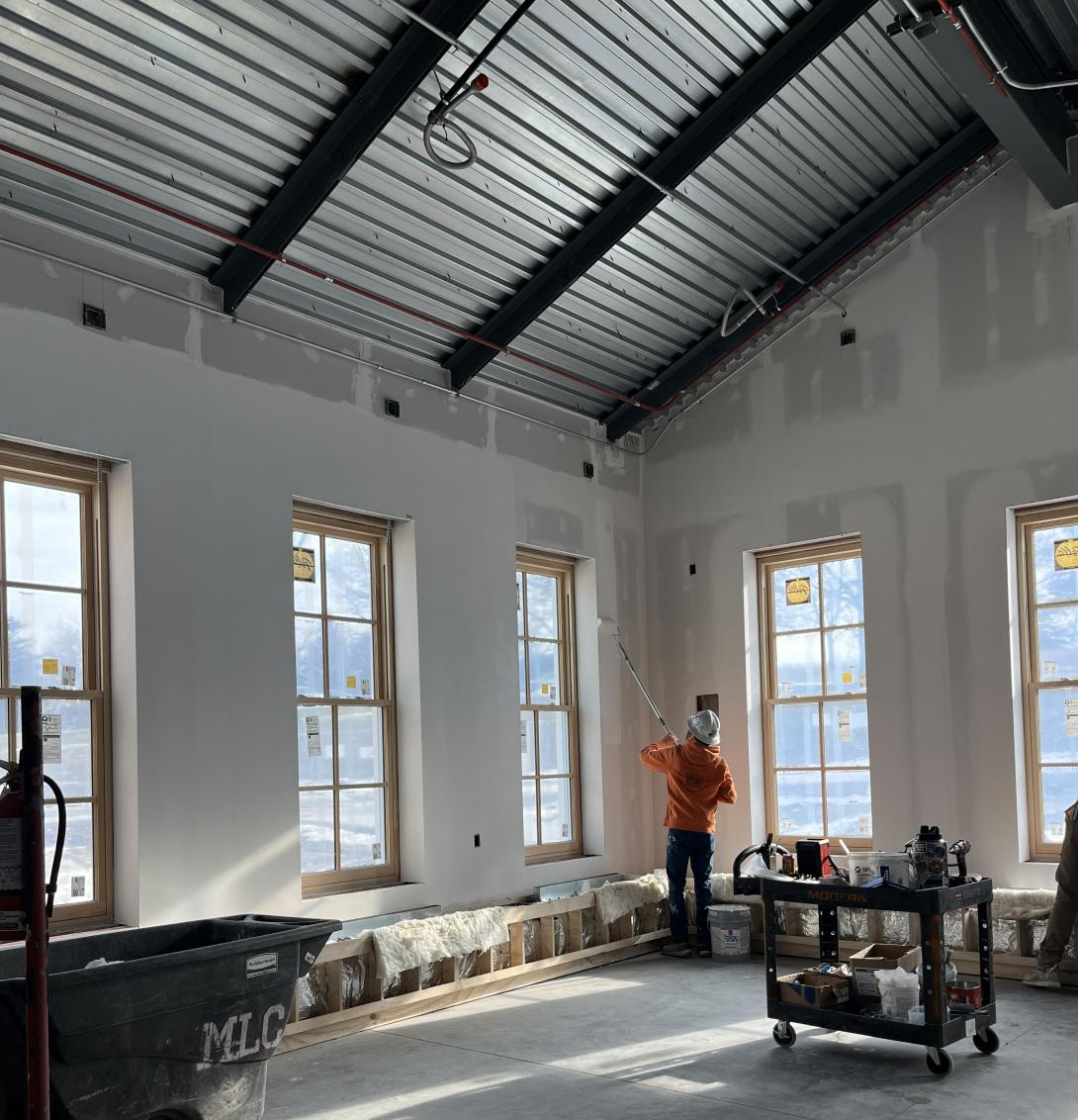 Worker painting wall of new lobby addition, December 23, 2025