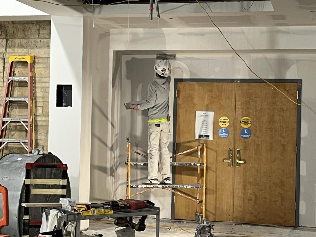 Worker finishing drywall around Auditorium doorway, January 21, 2026