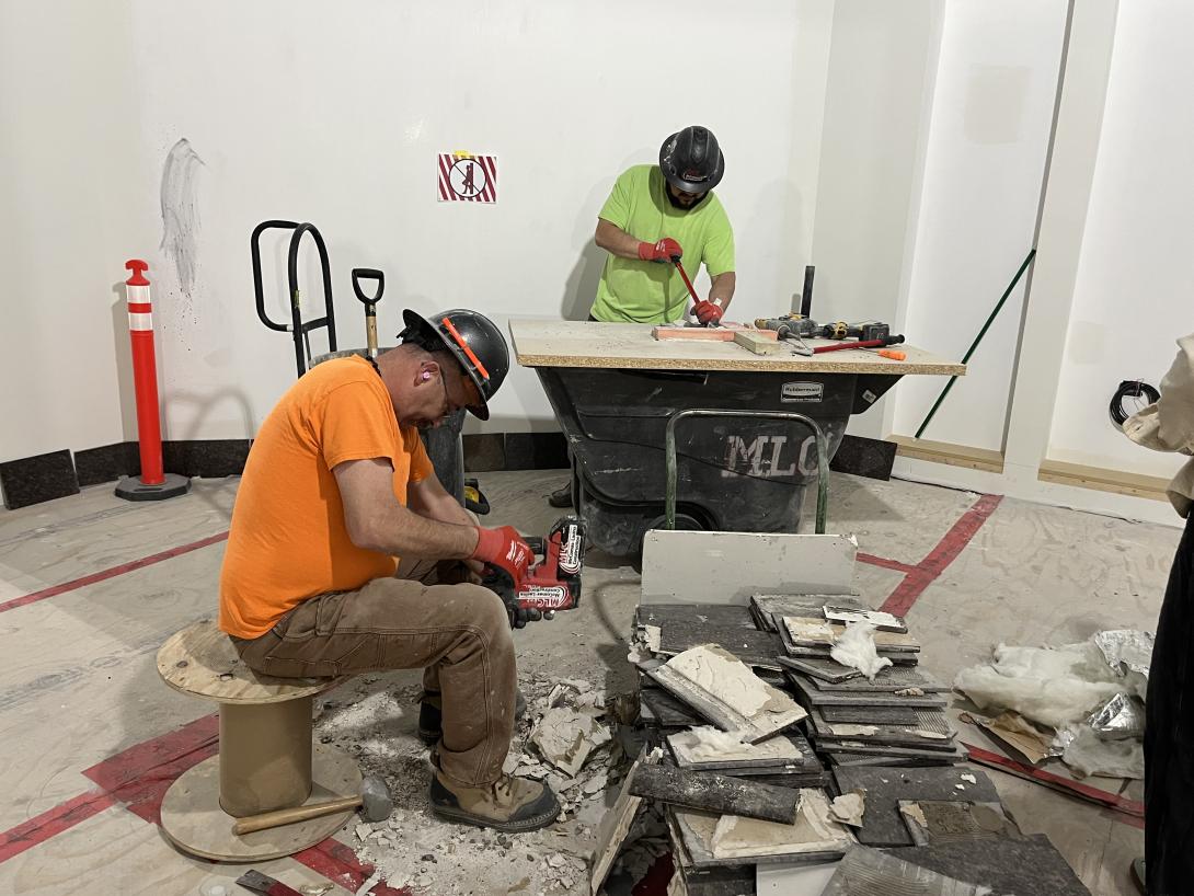 Workers remove adhesive on original marble tiles for placement in new Story Hub, March 4, 2026 