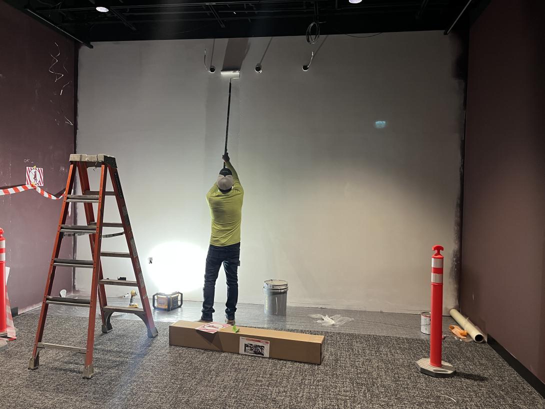 Worker paints gallery wall, March 11, 2026