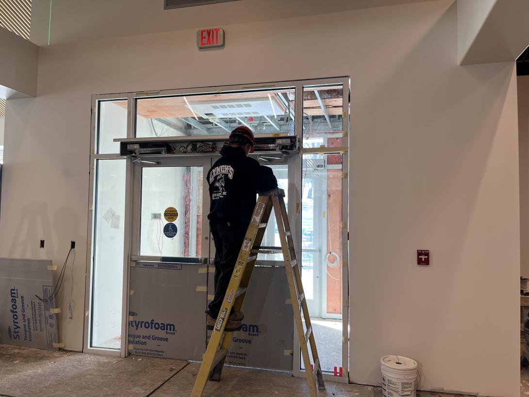 Worker setting up electronics for front entry doors, March 18, 2026