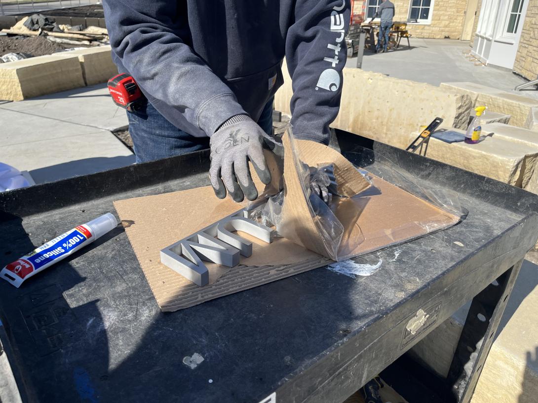 Worker removes Museum signage from packaging, April 8, 2026