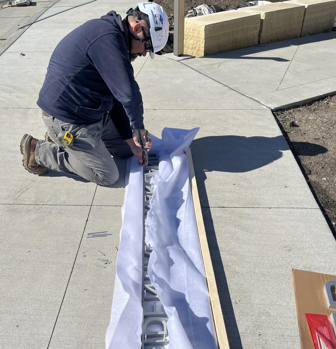 Worker removes Hoover Presidential Library signage from packaging, April 8, 2026