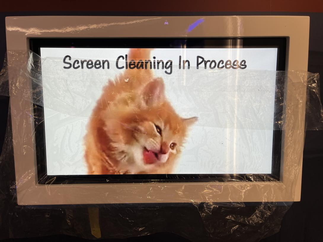 A playful image of a cat licking a screen captioned, "Screen Cleaning in Progress," May 27, 2026